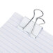 An assorted color small, medium, and mini Universal binder clip on a piece of paper.