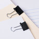 Two black Universal mini binder clips on a white surface.