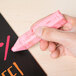 A person holding a pink Crayola chalk stick.