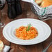 A Tuxton TuxTrendz bright white china pasta bowl filled with spaghetti and bread on a table.