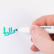 A person using a Universal dry erase marker to write "hello" on a piece of paper.