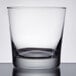 A close up of a Libbey rocks glass on a table with a white background.