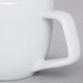 A close-up of a Tuxton bright white china creamer with a handle.