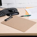 A brown Universal clipboard on a desk with a piece of paper and a pen.