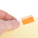 A hand holding a piece of paper with Avery 8-tab insertable dividers with an orange tab.