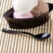 A close-up of a black Fineline Tiny Taster spoon in a bowl of ice cream.