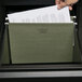 A hand putting a paper into a Universal Box Bottom Hanging File Folder in a file drawer.