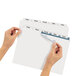 A pair of hands holding a white piece of paper with Avery Index Maker dividers.