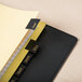 A black binder with Universal Leather-Look Month Tab Dividers featuring yellow labels.