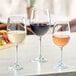 Acopa Select Flora wine glasses on a table with white wine and fruit.