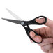 A hand holding Universal stainless steel scissors with a black handle.