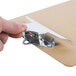 A hand holding a Universal brown hardboard clipboard with a metal clip.