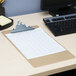 A brown Universal hardboard clipboard on a desk.