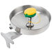 A T&S stainless steel wall mounted eye wash station with a round bowl, yellow lid, and green handle.