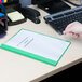 A hand holding a green Universal Office report cover with a clear cover and prong fasteners.