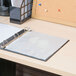 A table with a white Universal sheet protector on a binder with paper inside.
