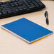 A blue National spiral bound notebook on a desk.