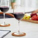 Two Acopa Select Flora wine glasses filled with red wine on a table.