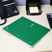 A green Five Star notebook on a table next to a telephone.