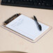 A Universal clear low profile clipboard with a pen and a piece of paper on it.