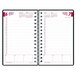 A black spiral-bound planner with a pink and white cover and black lines on the cover.