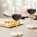 Two Acopa Select Blanc wine glasses on a table with a glass of wine and cheese and crackers.