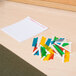 A pile of colorful plastic pieces next to a piece of paper on a table.