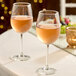A pair of Acopa Select Flora 12 oz. wine glasses filled with rosé wine on a table.