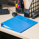 A light blue Universal Deluxe View Binder on a desk next to a computer.