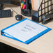 A light blue Universal Deluxe Non-Stick View Binder on a desk with a file folder inside.