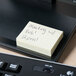 A yellow Universal sticky note on a black tray next to a keyboard.