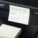 A Universal yellow sticky note with a meeting note attached to a printer.