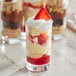 Three Acopa juice glasses filled with dessert and topped with whipped cream and strawberries.