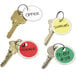 A group of keys with Avery assorted color card stock tags on them. The red tag has black text.