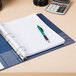 A Universal Royal Blue non-stick binder with a pen and calculator on a desk.