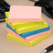 A stack of Universal assorted neon color self-stick notes on a desk.