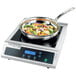 A Waring countertop induction range with a pan of vegetables on it.