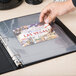 A hand placing a Las Vegas photo in an Avery 3-hole punched photo storage page in a binder.