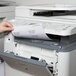 A hand putting a Universal White Permanent Laser and Inkjet Label into a printer.