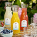 A close-up of Avery White Textured Matte Arched Labels on glass bottles of juice on a table.