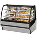 A True refrigerated bakery display case with different types of pastries and baked goods on a counter.