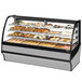 A True stainless steel curved glass dry bakery display case filled with pastries.