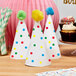 A pack of white Avery round labels with colorful polka dots on white cone-shaped party hats.