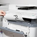 A person's hand putting a piece of Avery clear full-sheet labels into a printer.