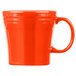 A close up of an orange Fiesta mug with a handle.