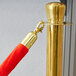 A Lancaster Table & Seating red rope with gold ends on a gold stanchion pole.