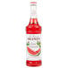 A bottle of Monin Premium Classic Watermelon Flavoring Syrup with red liquid inside.