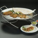 An American Metalcraft round stainless steel griddle stand with food on it on a table.