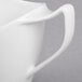 A close-up of a white Royal Rideau porcelain creamer with a handle.