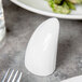 A white porcelain pepper shaker on a table.